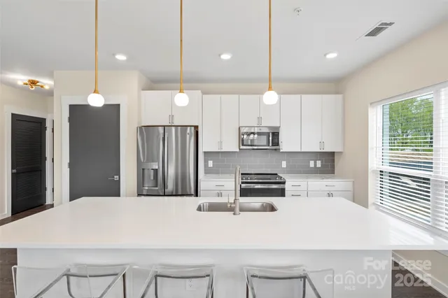 a kitchen with kitchen island a refrigerator a stove a sink and chairs with wooden floor