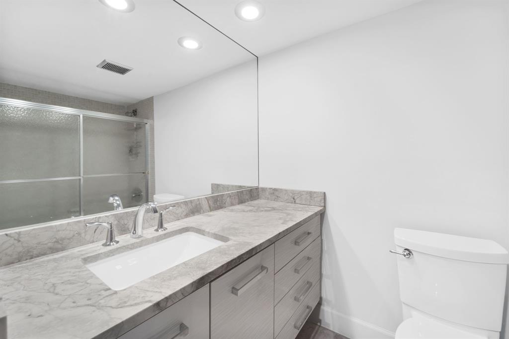 3010 North Course Drive, Unit 911 Pompano Beach, FL 33069 - Photo 9 of 13 a bathroom with a granite countertop sink a mirror and a toilet