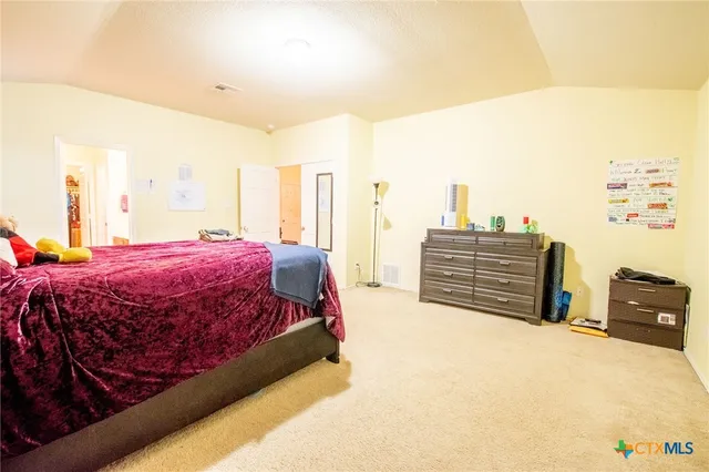 a spacious bedroom with a bed and dresser