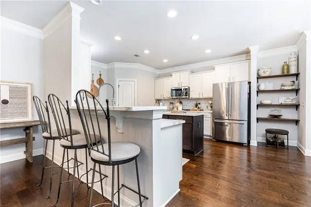a kitchen with stainless steel appliances wooden floor and a refrigerator