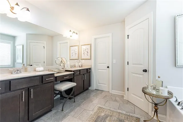 a spacious bathroom with a granite countertop sink a mirror and a bathtub