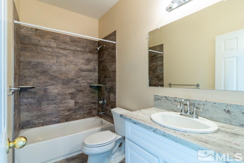 9630 Truckee Meadows Place Reno, NV 89521 - Photo 10 of 18 a bathroom with a granite countertop sink a toilet a mirror a bathtub and shower