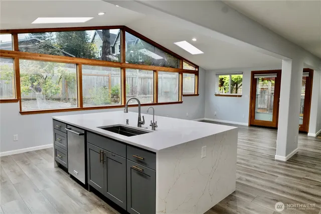 a kitchen with stainless steel appliances granite countertop a sink a stove and a wooden floor