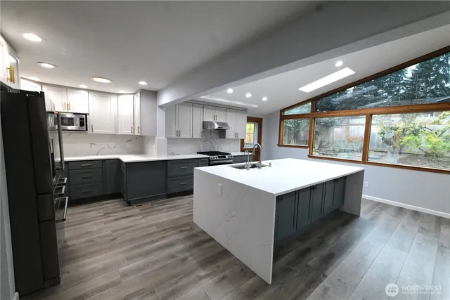 a kitchen with kitchen island a sink dishwasher stove and refrigerator with wooden floor