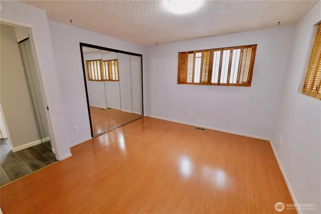 a view of an empty room with window and wooden floor