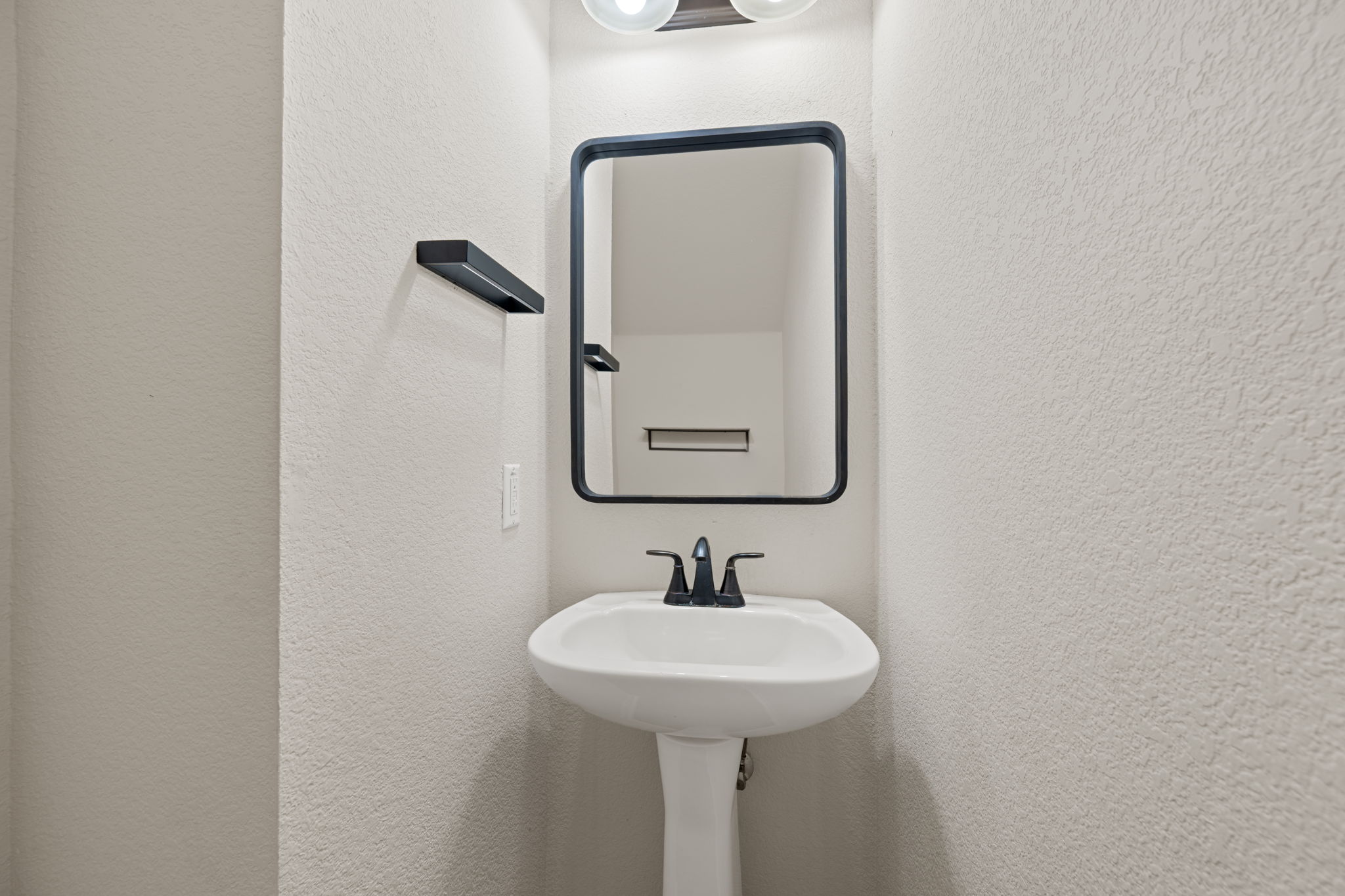 8902 Magna Carta Loop, Unit 122 Austin, TX 78754 - Photo 15 of 39 A compact and functional bathroom space featuring a sleek pedestal sink and contemporary mirror.