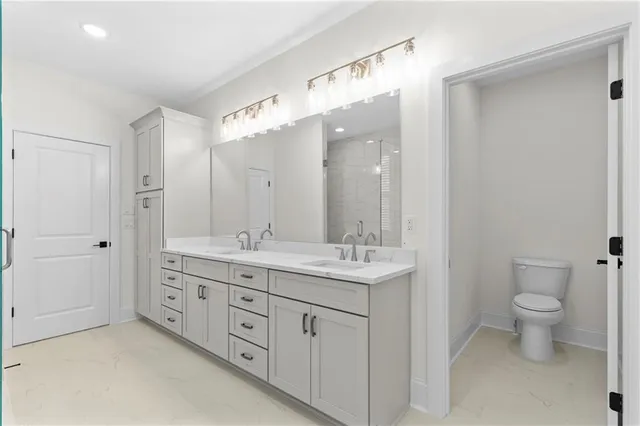 a spacious bathroom with a double vanity sink a toilet and a mirror