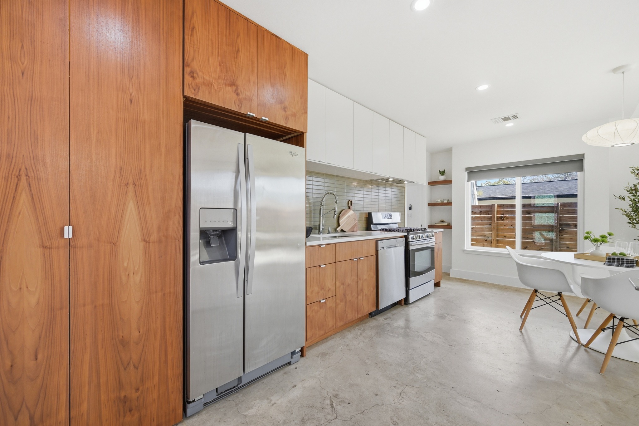 1805 Tillery Street Austin, TX 78721 - Photo 3 of 23 Kitchen with stainless steel appliances, two tone cabinetry, concrete floors, light countertops, and decorative backsplash