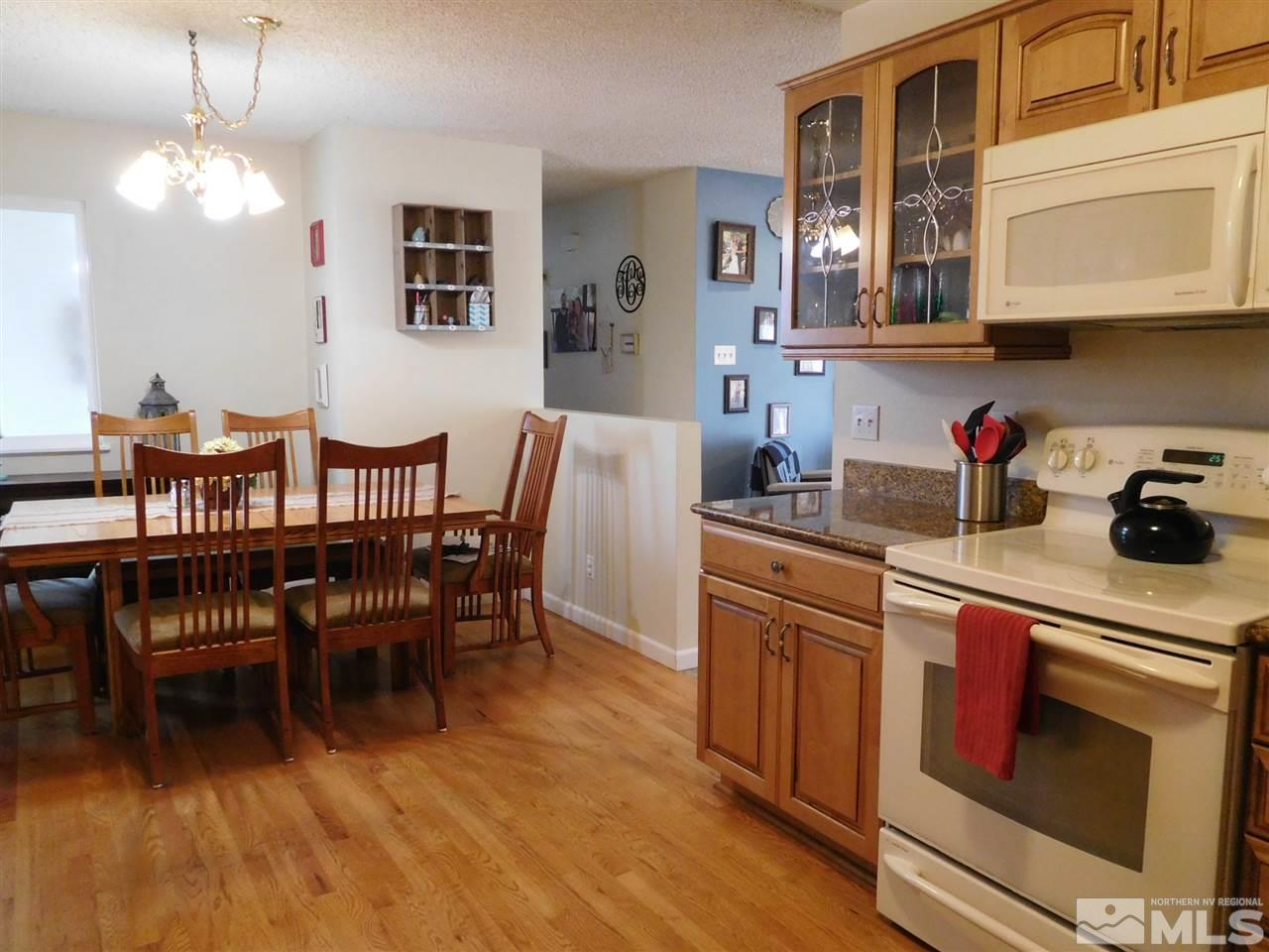 687 Ibis Lane Reno, NV 89503 - Photo 3 of 14 a kitchen with stainless steel appliances granite countertop a stove top oven a sink a dining table and chairs with wooden floor