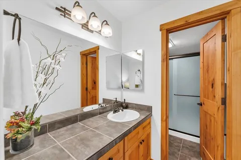 a bathroom with a granite countertop sink a mirror and a shower