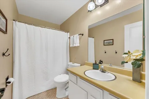 a bathroom with a granite countertop sink toilet and a mirror