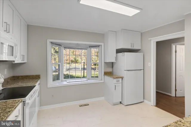 a kitchen with granite countertop white cabinets and white appliances