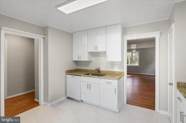 a kitchen with granite countertop white cabinets and white appliances