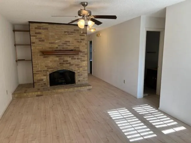 a view of an empty room with a fireplace and a window