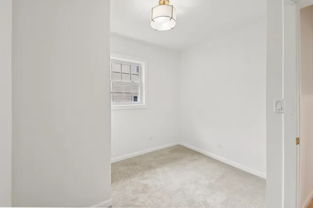 an empty room with a chandelier fan and windows