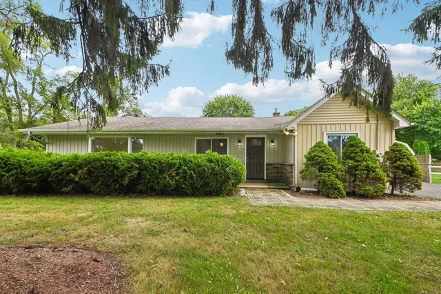 a front view of a house with a yard and potted plants