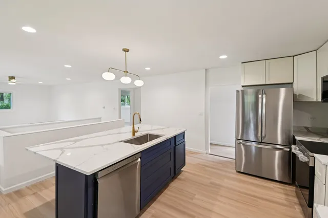 a kitchen with kitchen island white cabinets appliances and wooden floor