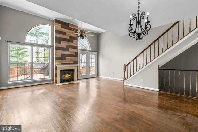 a view of an empty room with wooden floor a fireplace and a window