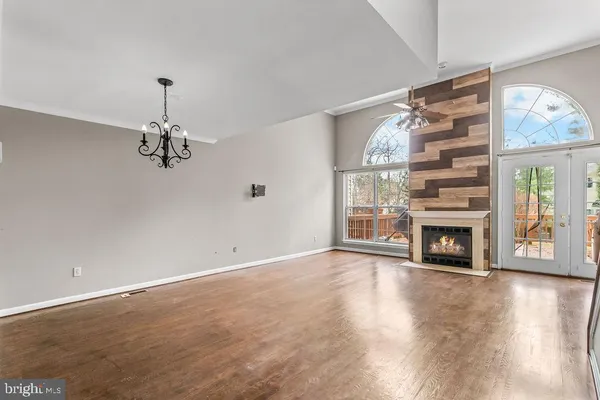 an empty room with windows fireplace and wooden floor