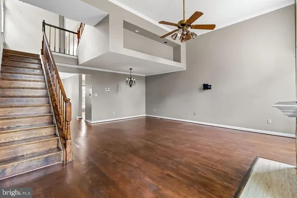 wooden floor in an empty room with a chandelier fan