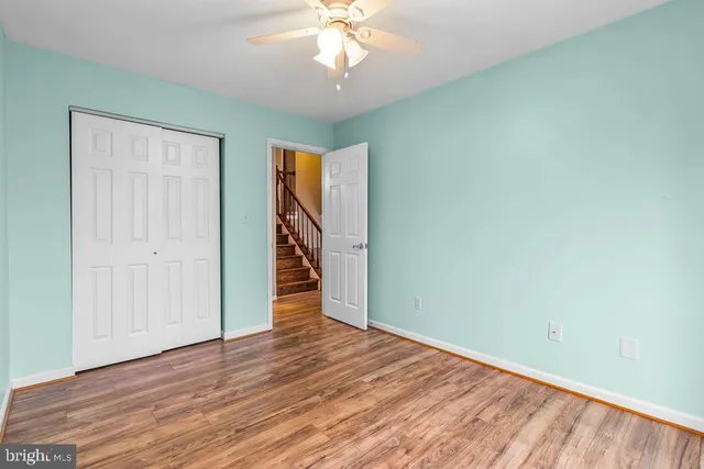 an empty room with wooden floor chandelier fan and windows