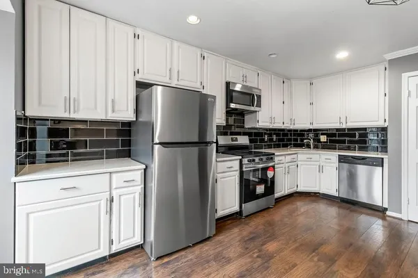 a kitchen with white cabinets and stainless steel appliances