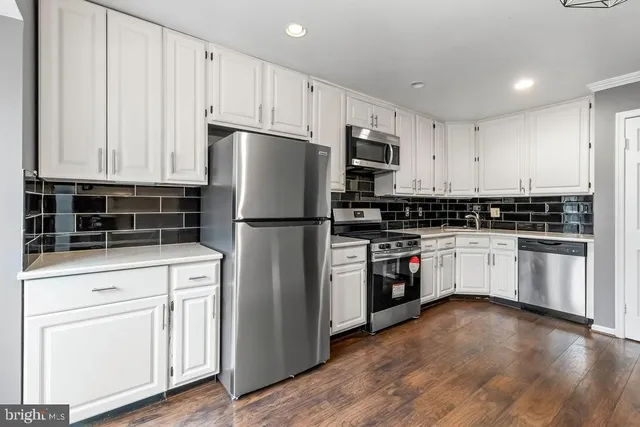 a kitchen with white cabinets and stainless steel appliances