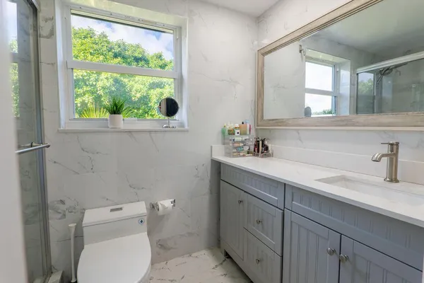 a bathroom with a toilet a sink a vanity a window and mirror