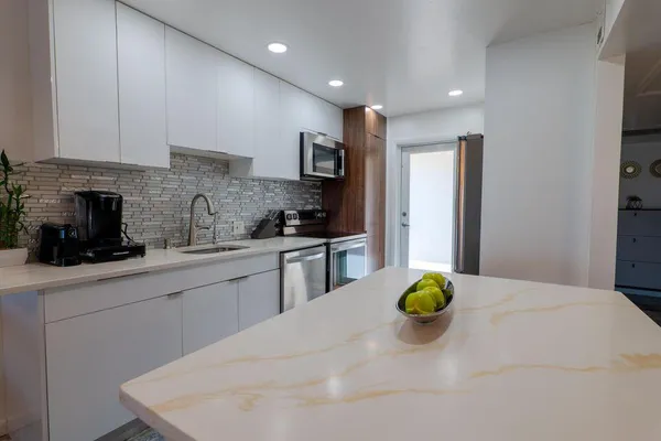 a kitchen with stainless steel appliances a sink a stove top oven a counter space and cabinets