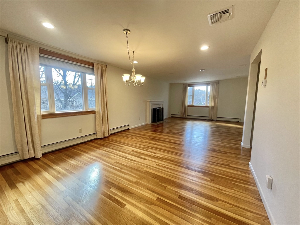 77 Louise Road, Unit 77 Newton, MA 02467 - Photo 2 of 22 an empty room with wooden floor and windows