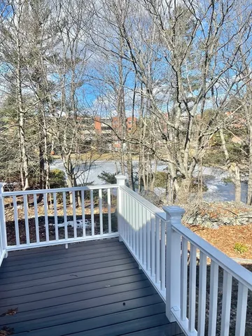 a view of a balcony with wooden fence and large trees