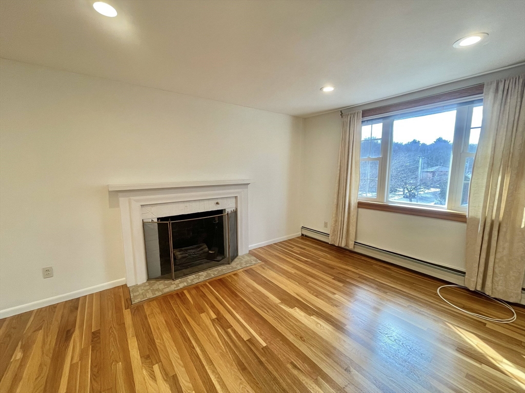 77 Louise Road, Unit 77 Newton, MA 02467 - Photo 4 of 22 a view of an empty room with wooden floor fireplace and a window