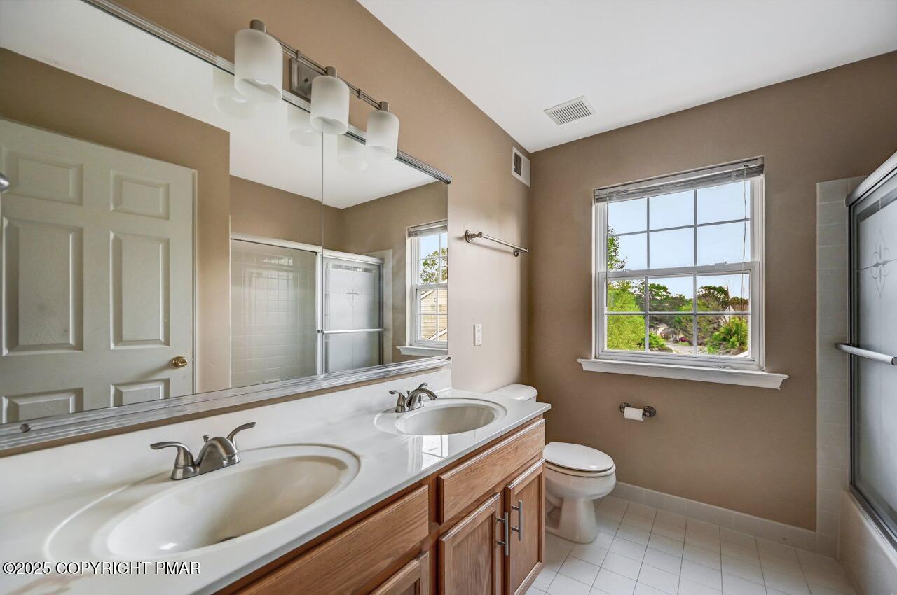 115 Daffodil Drive East Stroudsburg, PA 18301 - Photo 41 of 59 a bathroom with a granite countertop sink toilet a large mirror and a window