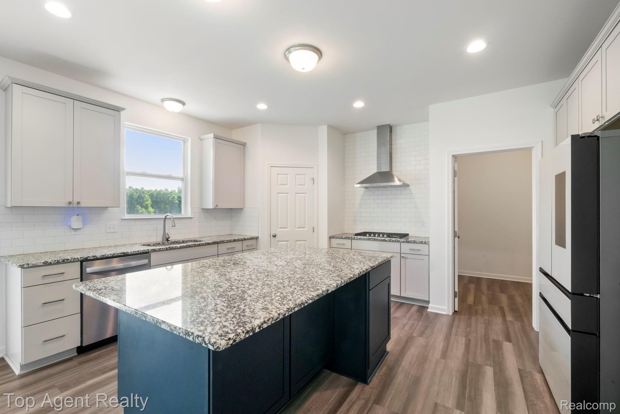63770 Dequindre Road Washington, MI 48095 - Photo 19 of 61 Modern kitchen featuring a central island with a stone-finish countertop, light-toned cabinetry, stainless steel appliances, and wood-finish flooring