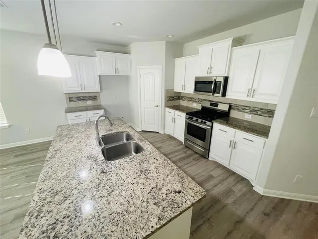 a kitchen with kitchen island granite countertop a sink stove and refrigerator