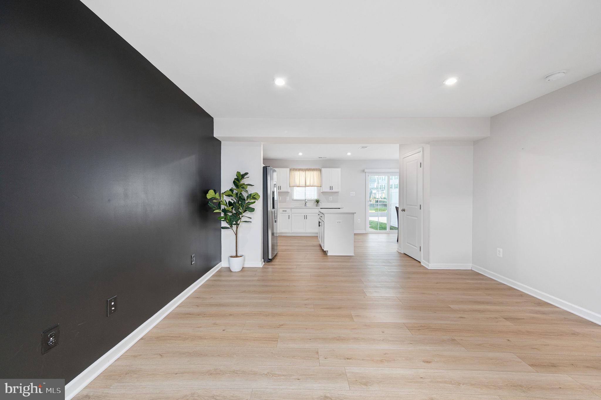 7233 Statesman Boulevard Ruther Glen, VA 22546 - Photo 11 of 31 a view of an empty room and kitchen with wooden floor