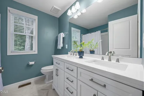 a bathroom with a double vanity sink a toilet and a mirror