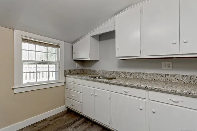 a kitchen with granite countertop white cabinets and a stove