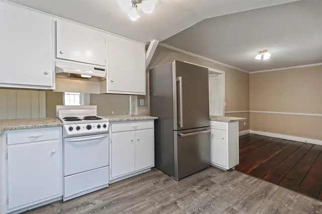 an empty room with windows fireplace and a wooden floor