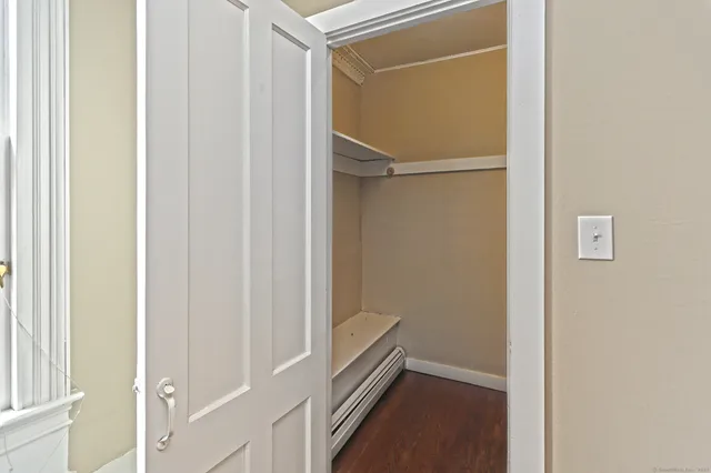 a view of an empty room with wooden floor fireplace and a window
