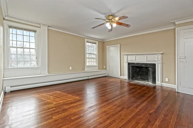 a view of an empty room with wooden floor fireplace and a window