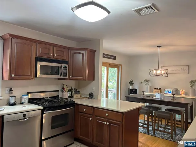 a kitchen with stainless steel appliances granite countertop a sink a stove and a wooden cabinets