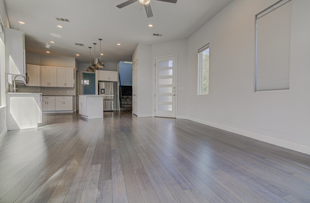 2406 East 16th Street Austin, TX 78702 - Photo 14 of 39 an empty room with wooden floor and kitchen view