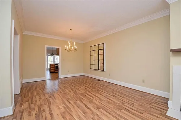 a view of an empty room with window and wooden floor