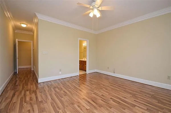 a view of an empty room with wooden floor and a ceiling fan