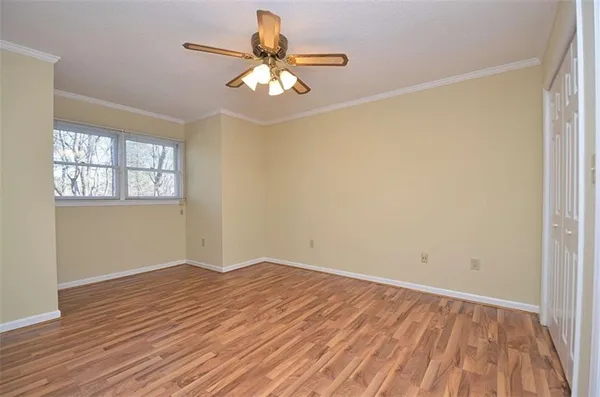 an empty room with wooden floor chandelier fan and windows