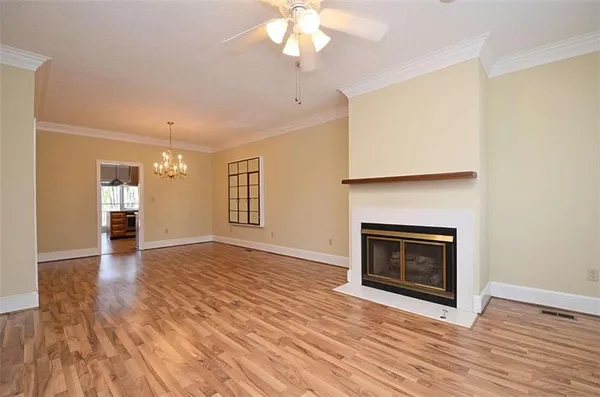 a view of an empty room with wooden floor fireplace and a window