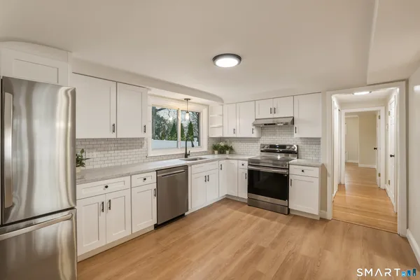 a kitchen with granite countertop a refrigerator stove top oven and sink