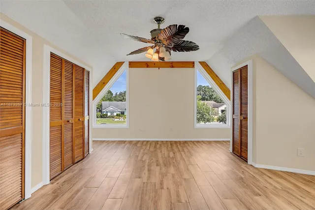 a view of empty room with wooden floor and fan