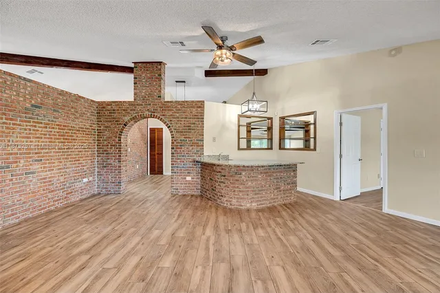 an empty room with wooden floor a ceiling fan and windows